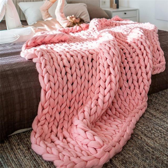 Knit throw blanket with chunky loop pattern spread flat on a bed