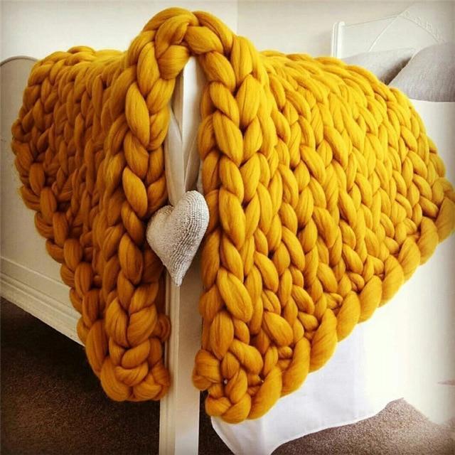 Knit throw blanket with chunky loop pattern draped over a bed frame