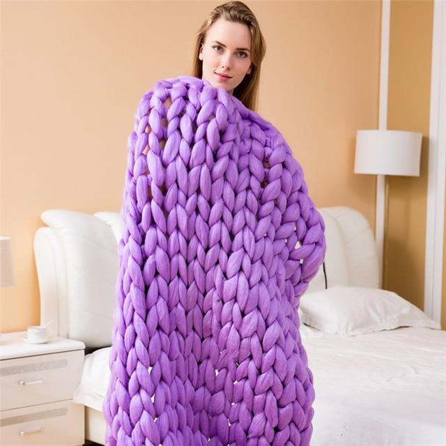 Woman holding a knit throw blanket in a standing position indoors