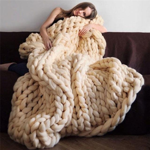 Woman seated on a sofa holding a folded knit throw blanket to her chest