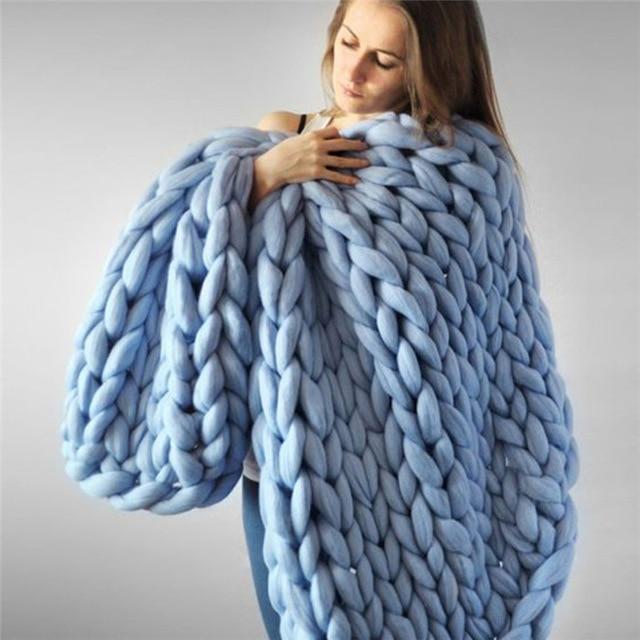 Woman standing wrapped in a knit throw blanket with looped texture