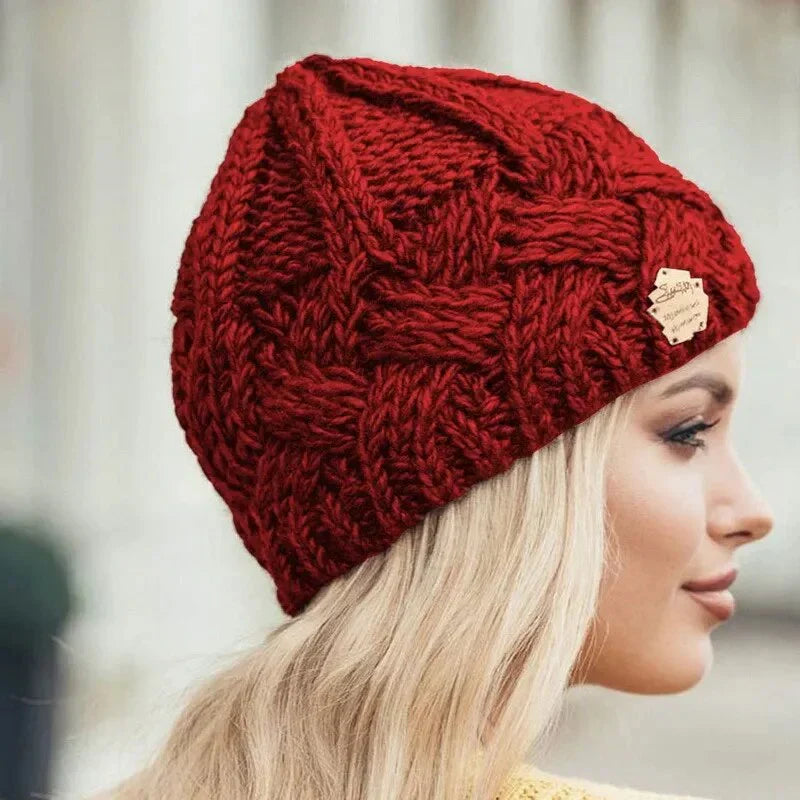 Red chunky cable-knit beanie with textured woven pattern and small front patch.