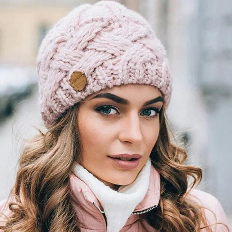 Light pink chunky knit beanie with braided cable pattern and small leather logo patch