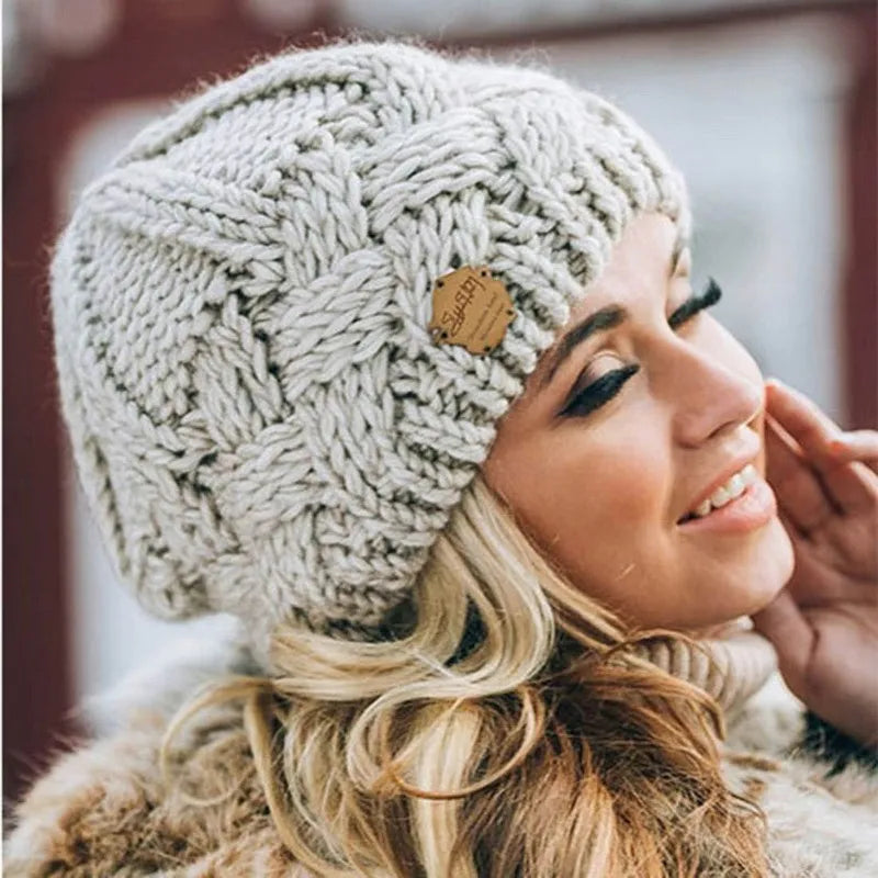 Light grey chunky knit beanie with braided cable knit texture and small leather logo patch