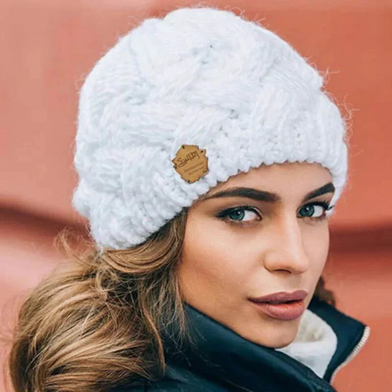 White chunky knit beanie with braided cable knit design and small leather logo patch