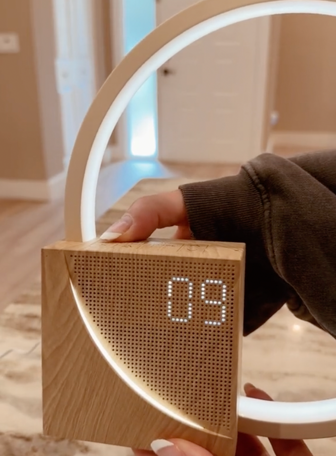 Plastic LED ring alarm clock with integrated light loop and front-facing digital screen, indoor