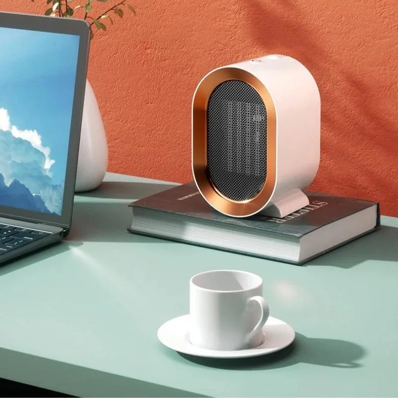 Small portable electric heater on a desk next to a laptop and coffee cup