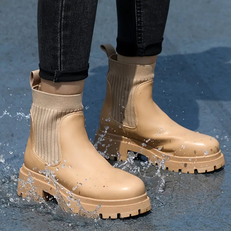 Beige waterproof chunky Chelsea boots with a smooth finish, stretch knit ankle panels, and treaded platform sole.
