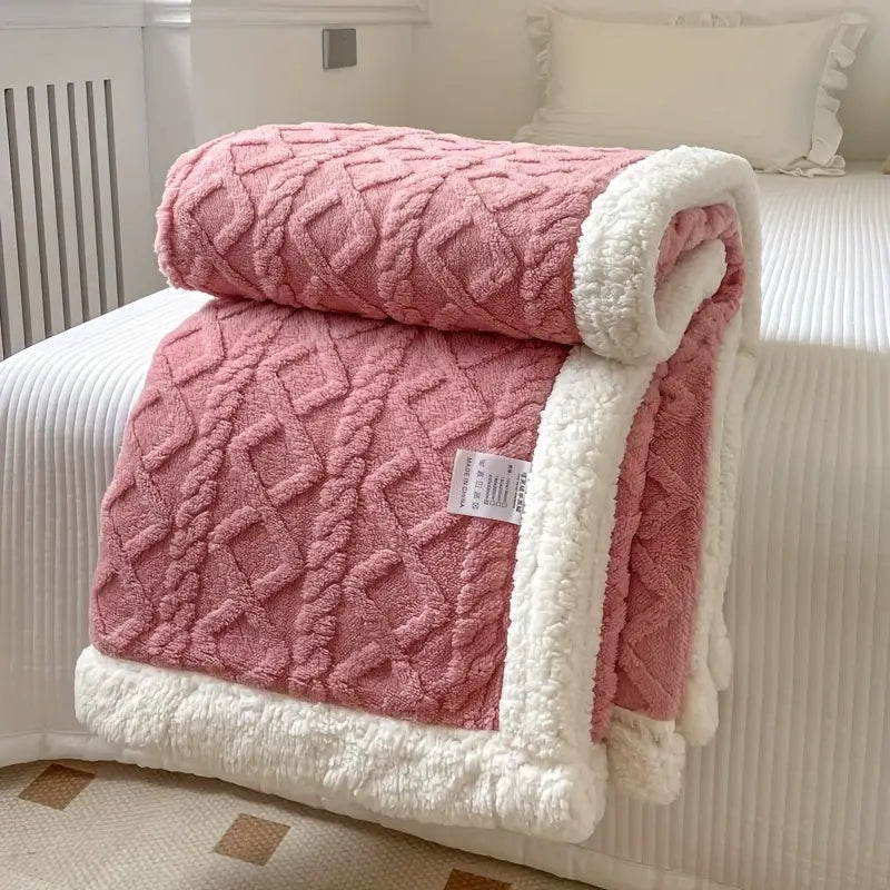 Dusty pink plush sherpa blanket with cable knit pattern and white sherpa trim.