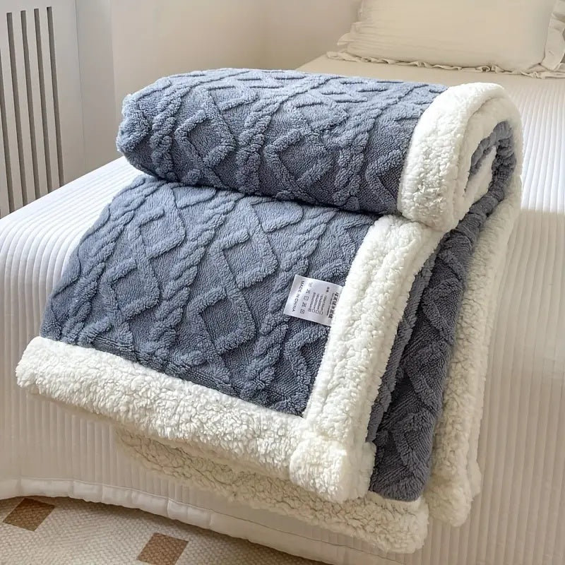 Blue-grey plush sherpa blanket with embossed pattern and white sherpa trim.